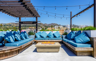 an outdoor patio with blue couches and a fire pit