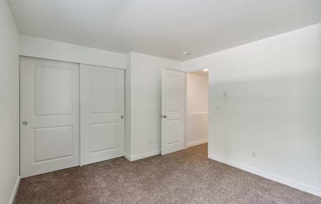 a bedroom with white doors and carpeting and white walls