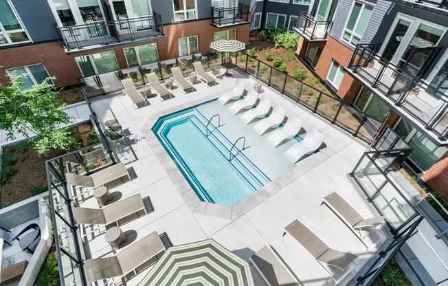 Courtyard pool with in-water loungers, sun seating, and surrounding balconies creating a social outdoor setting for warm-weather downtime.