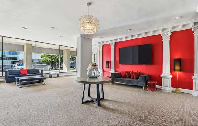 A living room with a grey carpet and a grey table with a vase on it.