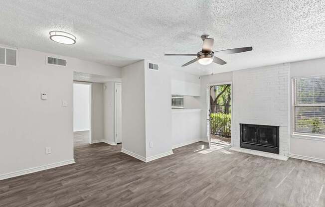 A spacious living room with a fireplace and a ceiling fan.