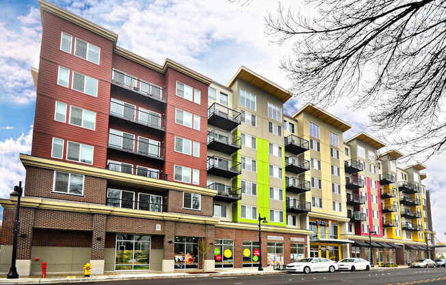 A row of multi-story apartment buildings with balconies and storefronts on the ground level.