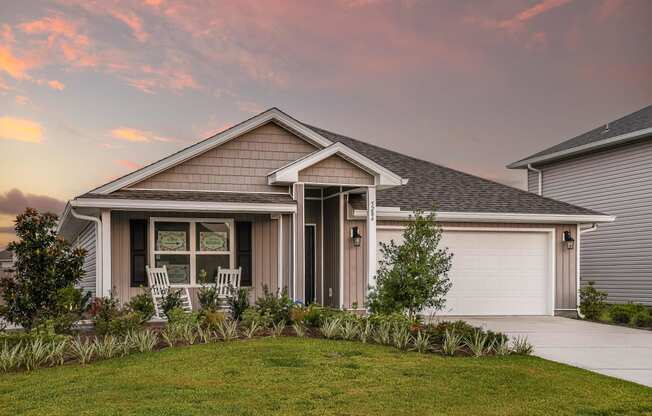 a home with a gray roof and a pink sunset in the background