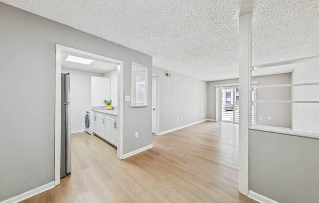 A kitchen with white appliances and wooden floors.