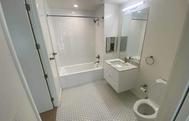 A white bathroom with a toilet, sink, and bathtub.at The Dillon, Los Angeles, CA