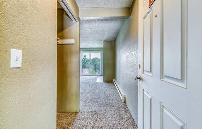 an empty hallway with a white door and a window