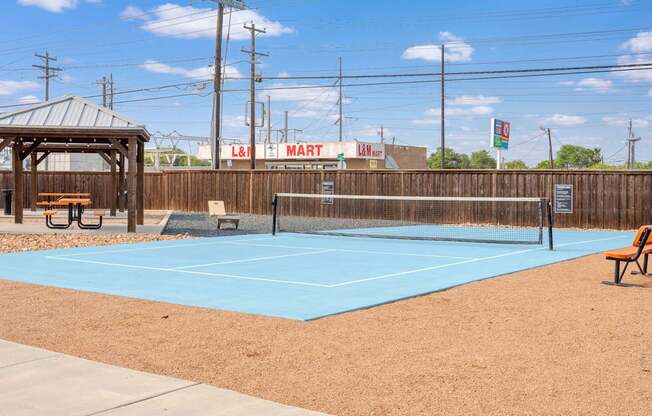 A tennis court with a blue surface and a wooden fence.