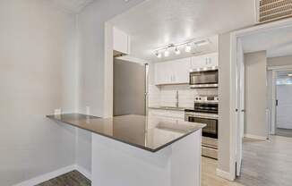 A kitchen with a stainless steel refrigerator and white cabinets.