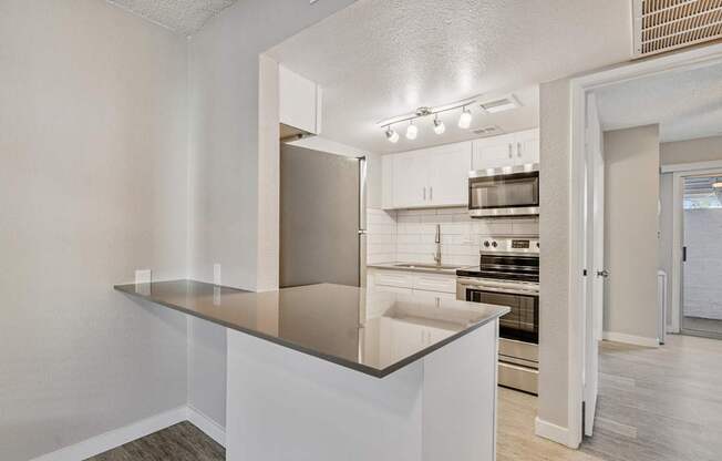 A kitchen with a stainless steel refrigerator and white cabinets.