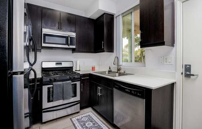 a kitchen with black cabinets and stainless steel appliances and a window