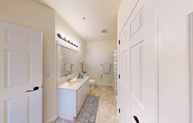 A white bathroom with a sink, mirror, and toilet.