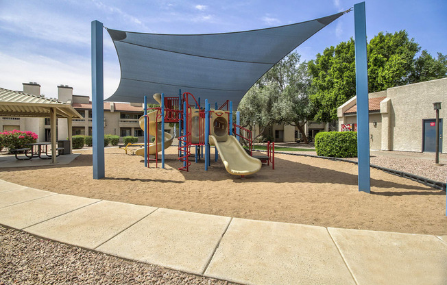 a playground with a swing set and slides in a courtyard