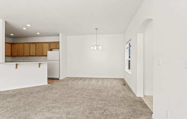 a spacious living room with a kitchen in the background