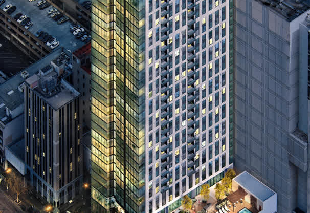 A tall building with a green roof is surrounded by other buildings.