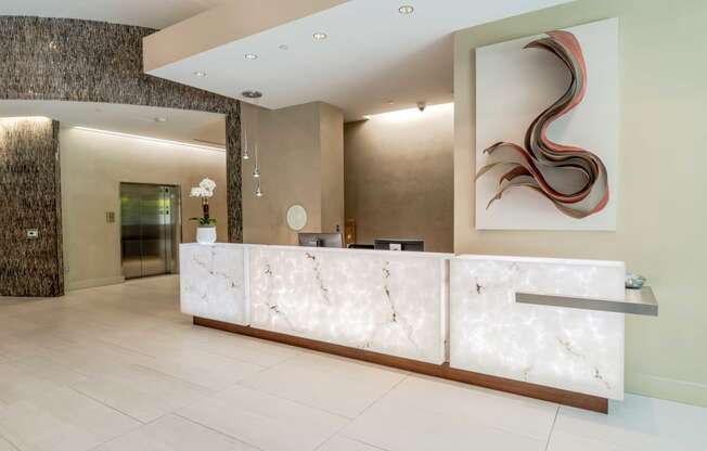 a reception desk in a hotel lobby with a painting on the wall