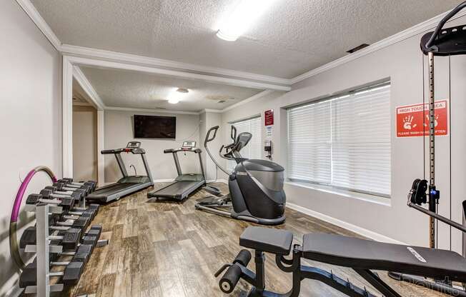 a gym with cardio machines and weights in a room with a window