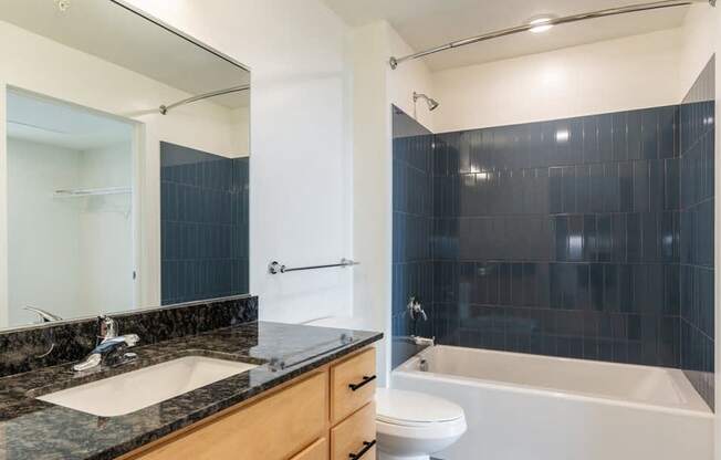 A modern bathroom with a black tiled shower area.