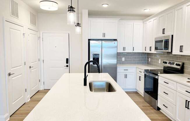 A kitchen with white cabinets and a marble countertop.