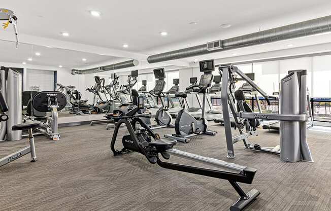 a gym with various cardio machines and weights on the floor