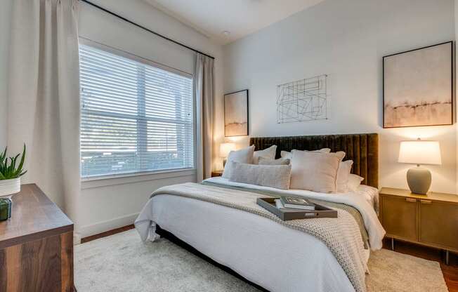 A bedroom with a large bed and two lamps.