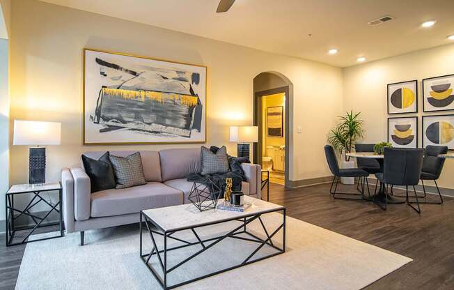 A living room with a grey couch, a coffee table, and a painting on the wall.
