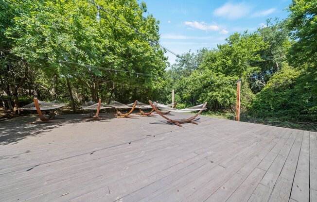 a deck with hammocks and trees in the background
