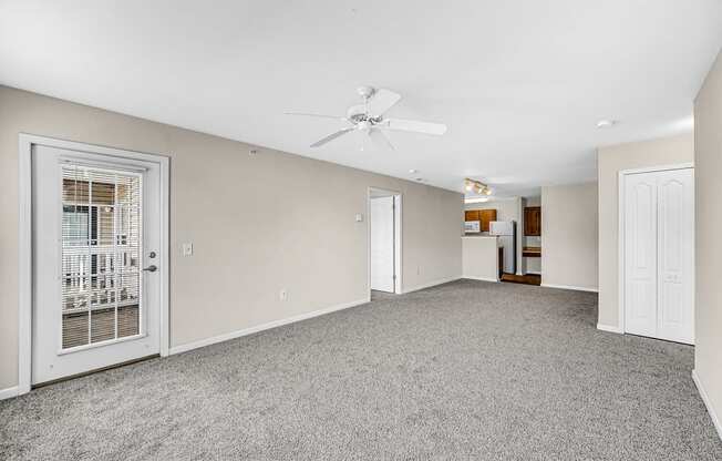 an empty living room with a white door and a ceiling fan