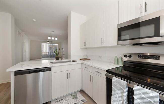 A modern kitchen with white cabinets and stainless steel appliances.