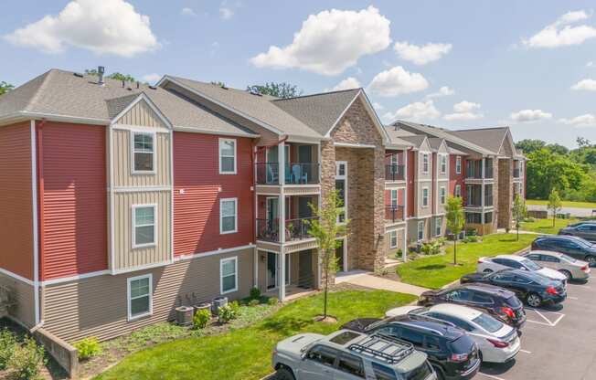 a row of apartment buildings with cars parked in a parking lot