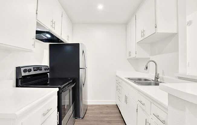 A kitchen with black appliances and white cabinets.