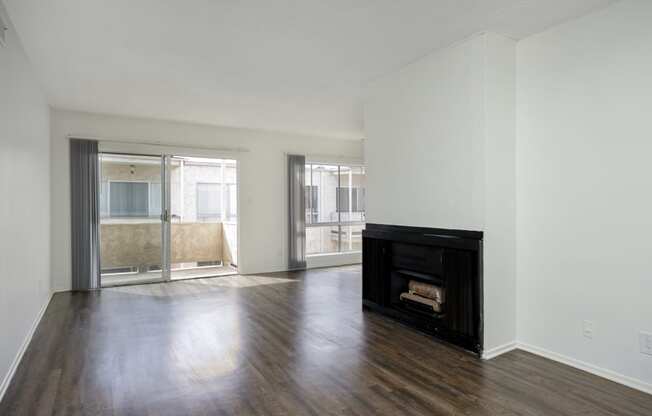 an empty living room with a fireplace and wooden floors