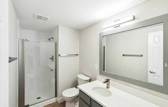 A white bathroom with a toilet, sink, and shower.