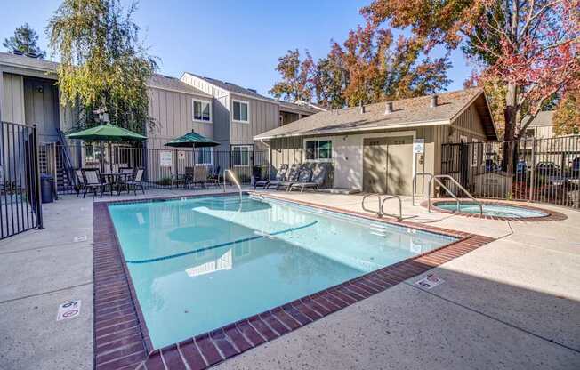 A swimming pool surrounded by a fence and a gazebo in the background.