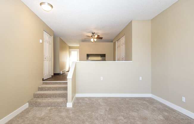 an empty living room with carpet and a ceiling fan