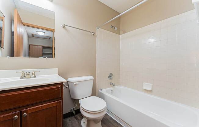 A white toilet sits next to a white bathtub in a bathroom.