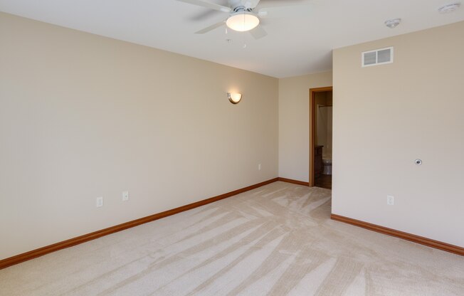 a empty living room with a ceiling fan and a white wall