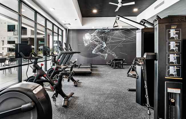 A gym with a variety of exercise equipment including treadmills, stationary bikes, and weight machines.