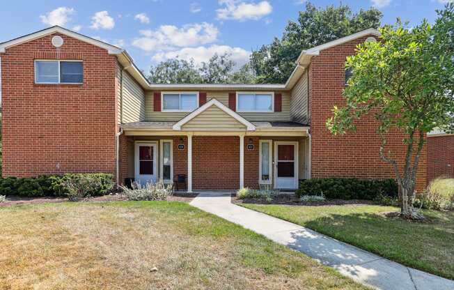 a brick house with a sidewalk in front of it