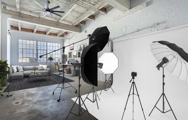 A photography studio with a ceiling fan, lighting equipment, and a couch.