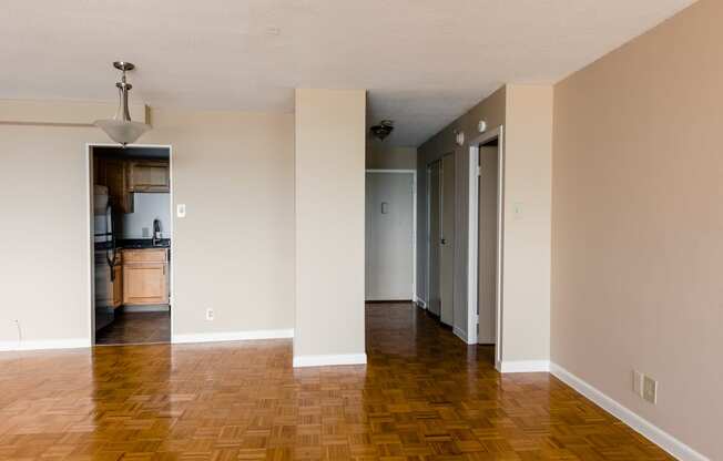 an empty living room with a hard wood floor and white walls at Hampton Plaza Apartments in Towson, MD 21286