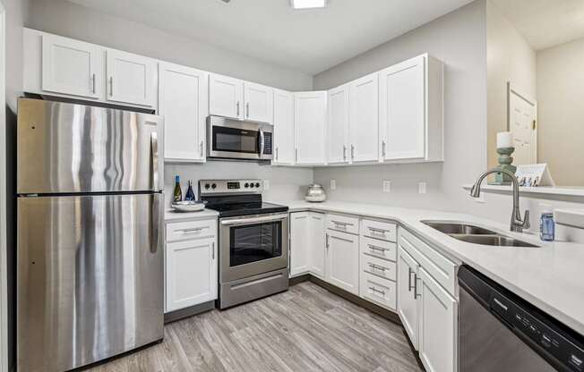 A modern kitchen with white cabinets and stainless steel appliances.