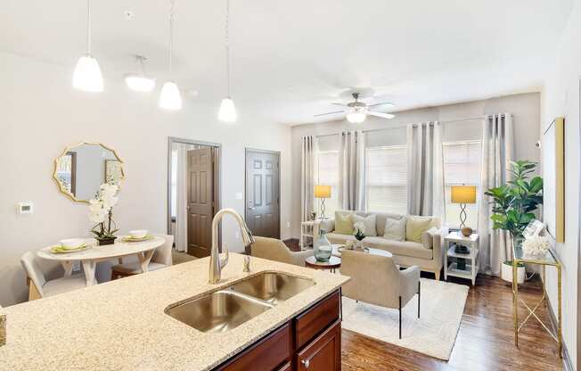 a living room and kitchen with a sink and a ceiling fan