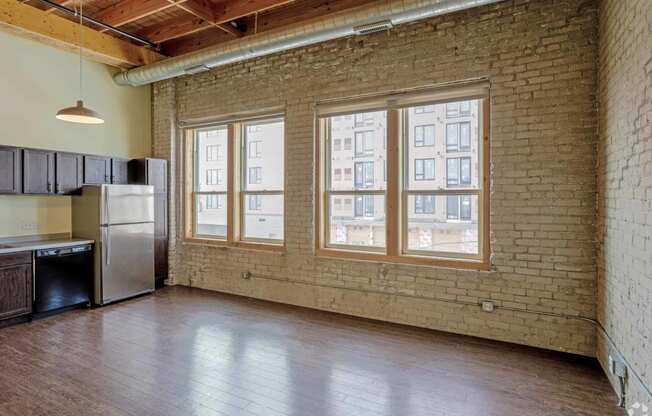 an empty living room with brick walls and a large window