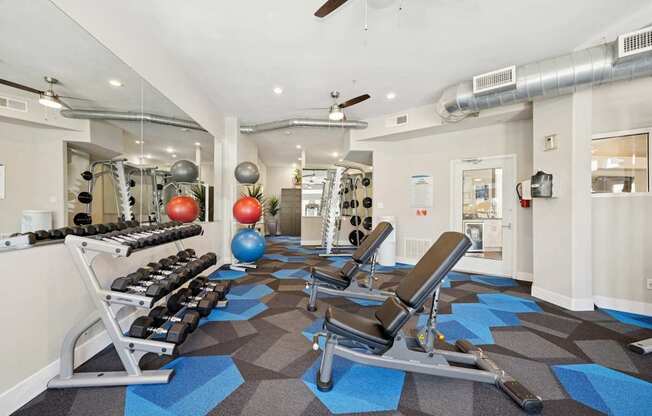A gym with a variety of equipment including weights and a rowing machine.