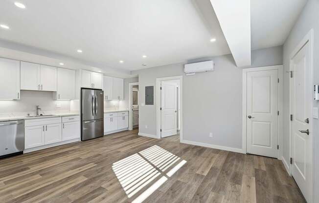 A kitchen with white cabinets and a wooden floor.