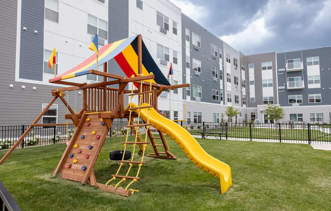 a playground with a swing set and a slide in an apartment building at Technology Park Apartments, Rochester