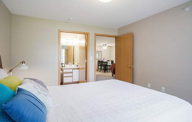 Furnished bedroom with a bed and a door to a bathroom and living area