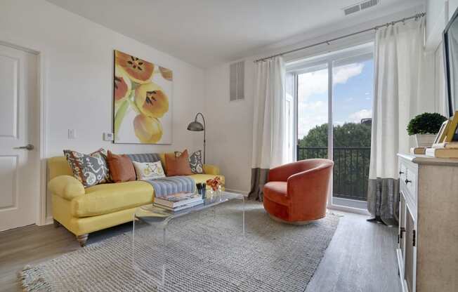 a living room with a yellow couch and a chair and a large window