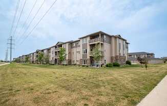 a large grassy area with an apartment building in the background