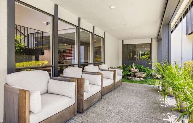A white couch is in the middle of a patio with a glass wall.